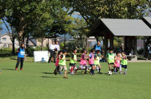輝くような芝の上でサッカー教室に励む子供たち