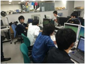 「ライブ配信チーム」。手前から二人目の若者が「読み上げ」担当。それをもとに「内容入力」をする担当が右側で、「位置情報入力」を担当するのが左側の若者。奥の若者がテキスト入力。もの凄い連携スピードだ。