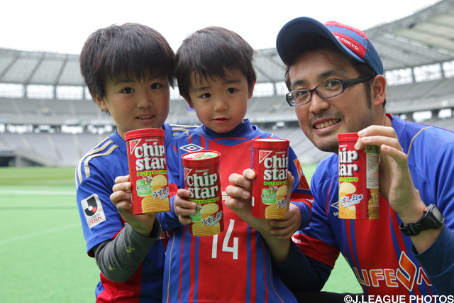 お菓子を手に持ち笑顔のＦＣ東京ファン・サポーター
