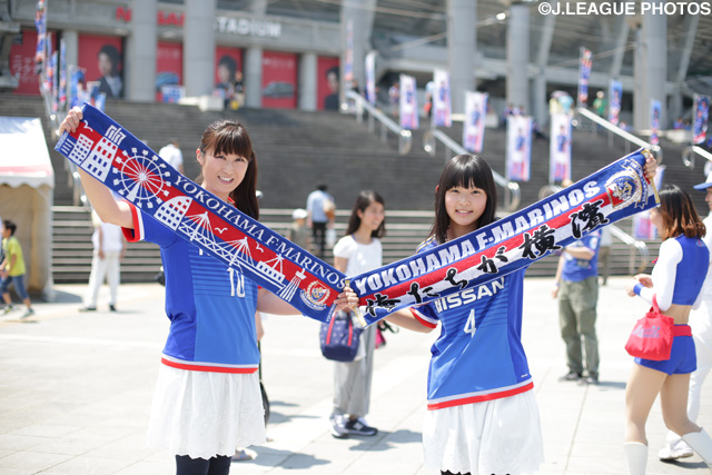 オリジナルのタオルマフラーを手に持ち笑顔の横浜FMのファン・サポーター