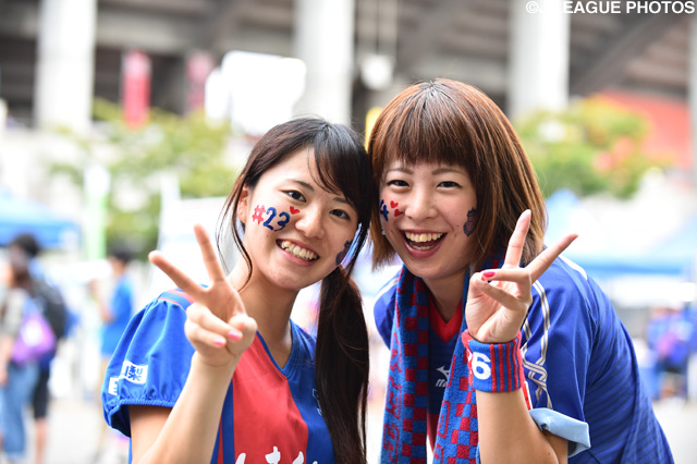 笑顔でピースサインをする甲府のファン・サポーター