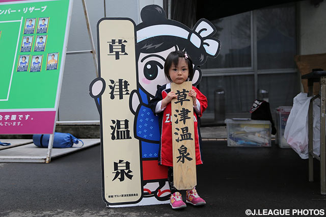 草津温泉のパネルを前でアウェイ金沢のちびっこサポーターが記念撮影【明治安田Ｊ２ 第2節 群馬vs金沢】
