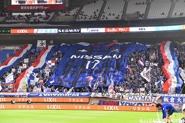 巨大なユニフォーム型フラッグを広げる横浜FMのファン・サポーター【明治安田Ｊ１ 1st 第12節 鹿島vs横浜FM】