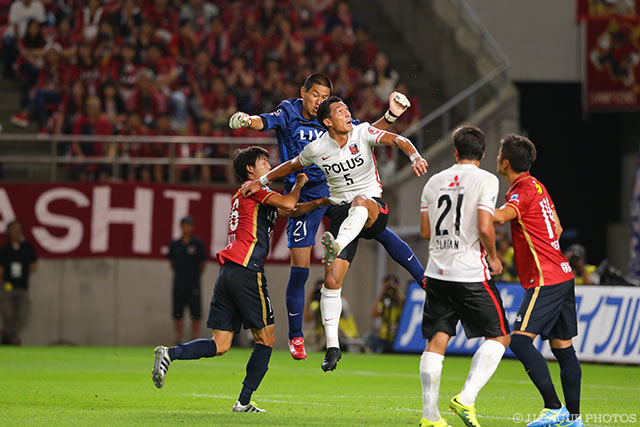 空中で激しく競り合う曽ヶ端 準（鹿島）と槙野 智章（浦和）【明治安田Ｊ１ 2nd 第5節 鹿島vs浦和】