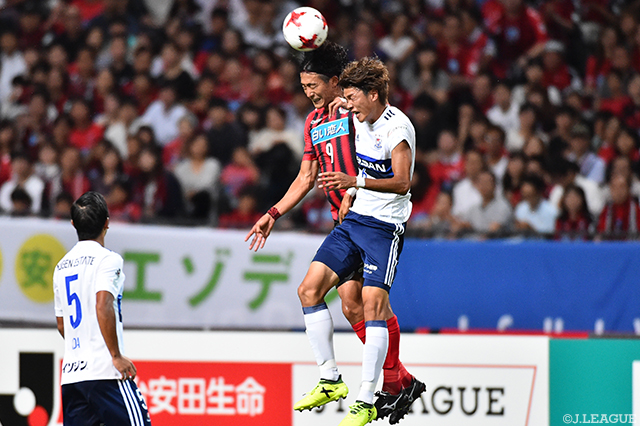 空中で激しく競り合う都倉 賢（札幌）と扇原 貴宏（横浜FM）【明治安田Ｊ１ 第21節 札幌vs横浜FM】