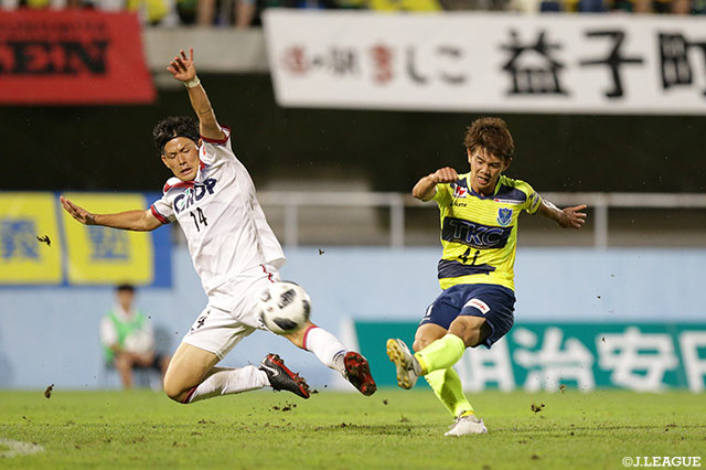 シュートを放つ西谷 優希（栃木）とブロックに入る上田 康太（岡山）【明治安田Ｊ２ 第31節 栃木vs岡山】
